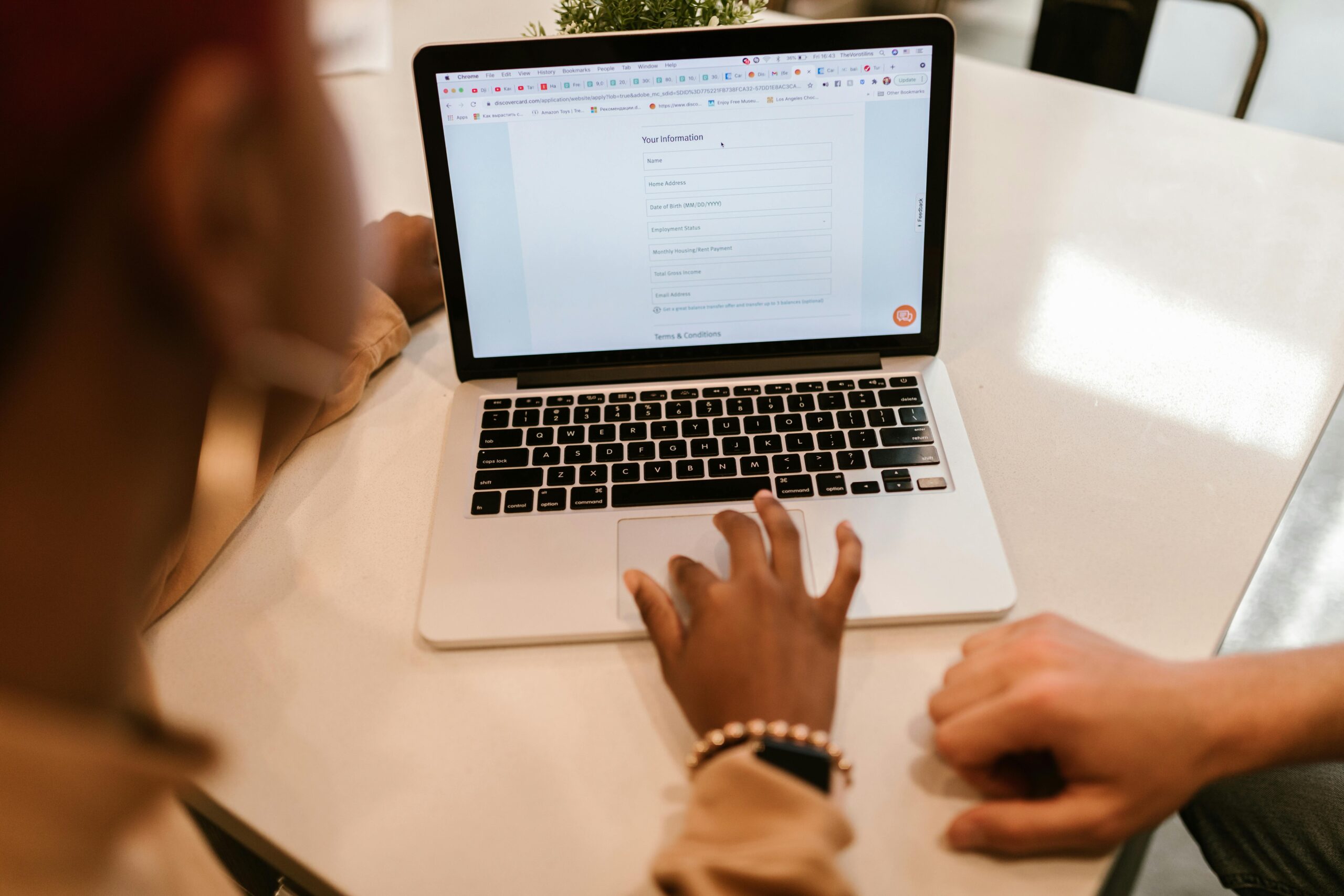 A white man and a black woman sat at a laptop.