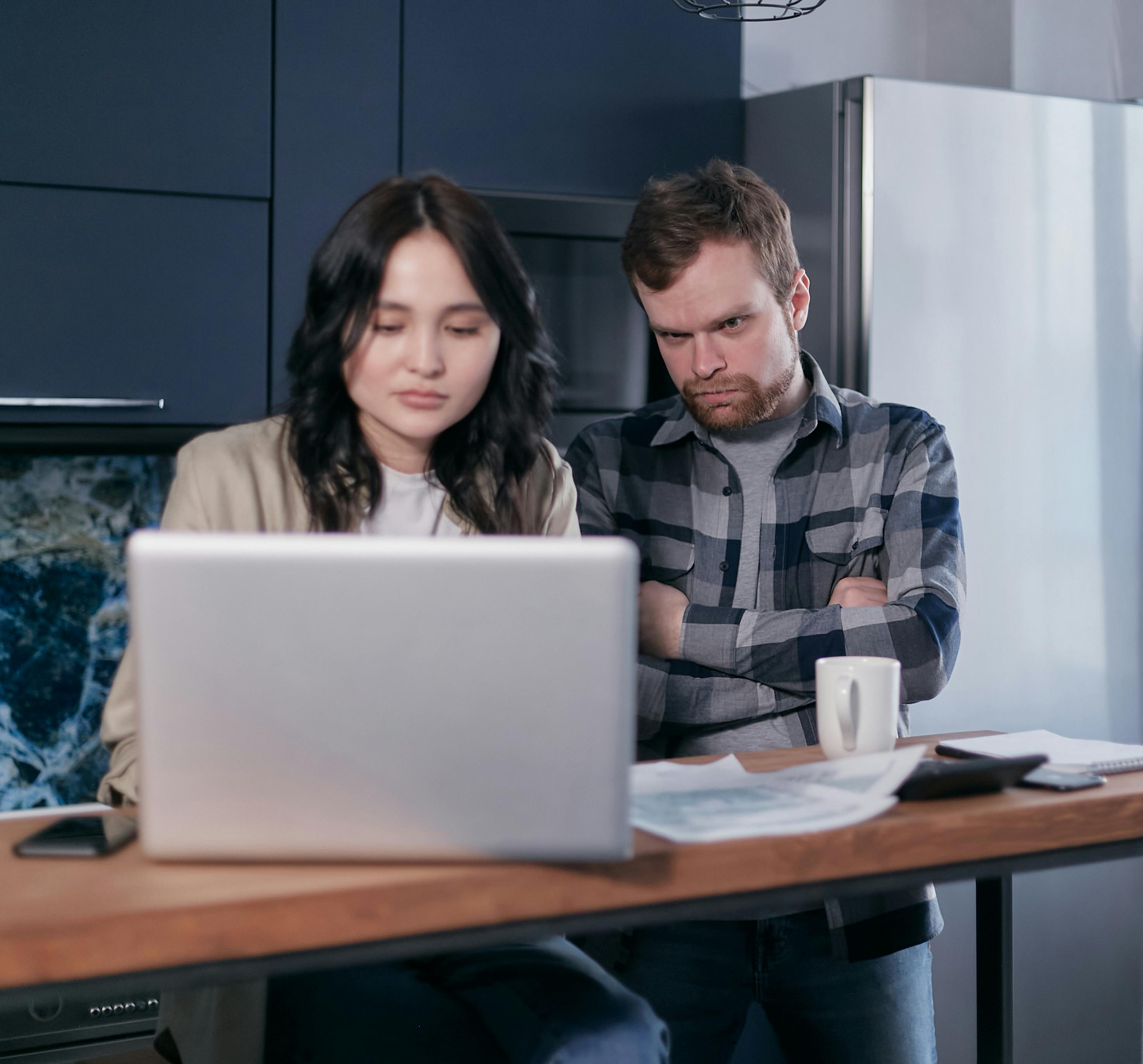 An asian woman and a white man working on a laptop.